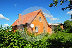 Cozy Brick House with Old faded red metal roof tile and chimney outdoor. Bad Roofing Exterior.