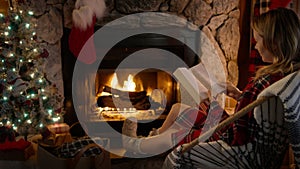 Cozy burning fireplace at home decorated for Christmas, Relaxed female in chair