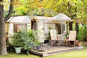 Cozy Campsite on caravan or camper van in forest. Trailer of mobile home stands in garden in camping.