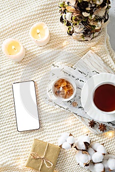 Cozy Christmas composition with mobile phone, gift boxes, Christmas tree, candles and a cup of tea. Flat lay, top view, sample,