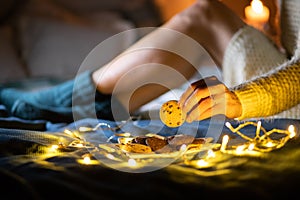 cozy Christmas at home woman in wool socks in bed eating cookies