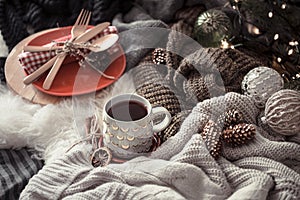 Cozy Christmas morning with cup of tea in bed. Still life scene with sweaters. Steaming cup of hot coffee, tea. Christmas concept