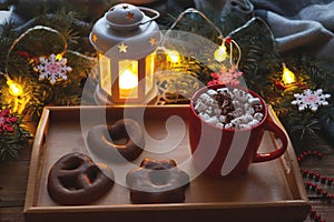 Cozy Christmas postcard with red cup of hot chocolate with marshmallows, glazed gingerbread on a tray, Christmas tree