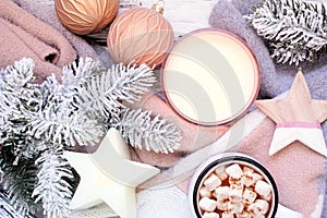 Cozy Christmas or winter scene with grey and dusty pink sweater, candle, hot chocolate, snowy branches and decor