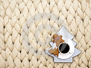 Cozy composition, closeup merino wool blanket, warm and comfortable atmosphere. Knit background. Cup of coffee and ginger cookies.