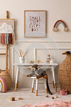 Cozy composition of kids room interior with mock up poster frame, white desk, animal wicker basket, plush monkey toys, rainbow