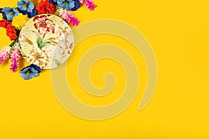 Cozy concept, composition decorative flowers and a beautiful saucer on a yellow background, top view, flat lay, isolated