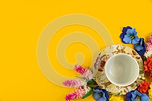 Cozy concept, yellow isolated background, tea party set with flowers, top view and copy space, border
