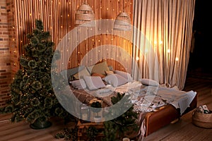 Cozy decor in the interior of the New Year`s room, Christmas tree, garlands, gifts, bed. Festive atmosphere in the house