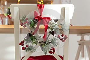 Cozy decorated with Christmas decorations with red ribbon and fir branches white kitchen chair