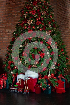 Cozy decorated living room for Xmas. Toy vintage train on floor under decorated Christmas tree and gifts. Red sack santa claus wit