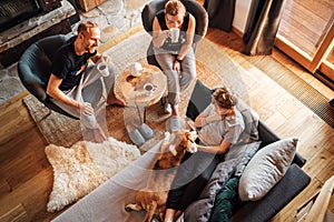 Cozy family tea time. Father, mother and son  at the home living room. Boy lying in comfortable sofa and  stroking their beagle