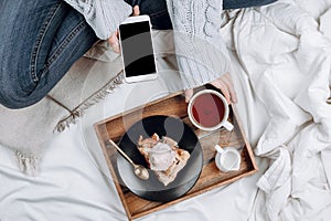 Cozy flatlay of bed with wooden tray with vegan apple pie, ice cream and black tea