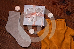 Cozy flatlay. Winter concept. Flat lay of knitted sweater, candles, needles and yarn on wooden background. Warm weekend