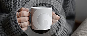 The cozy hands holding a blank white mug in a soft sweater..AI generated image