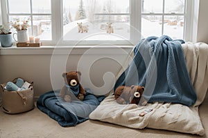 Cozy holidays at home. Cute little lying under blue knitted blanket with teddy bear on floor at window reading book. Winter season