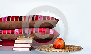 Cozy home interior decor: apple, stack of books, pillows and plaid on a white table. Distance home education. Quarantine concept