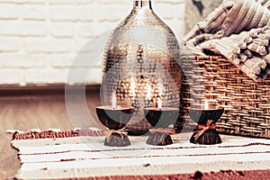 Cozy home interior decor, burning candles on a multi-colored rug on the background of a metal vase