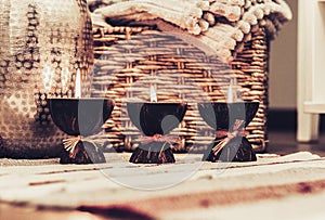 Cozy home interior decor, burning candles on a multi-colored rug on the background of a wicker straw box - Image