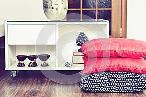 Cozy home interior decor, burning spa aroma candles in coconut shell, metal vase, pile of books, on white glass nightstand with