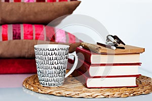 Cozy home interior decor: cup of coffee, stack of books, pillows and plaid on a white table. Distance home education. Quarantine