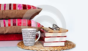 Cozy home interior decor: cup of coffee, stack of books, pillows and plaid on a white table. Distance home education. Quarantine