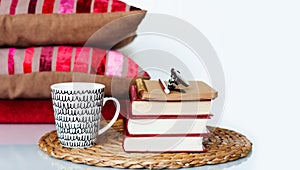 Cozy home interior decor: cup of coffee, stack of books, pillows and plaid on a white table. Distance home education. Quarantine