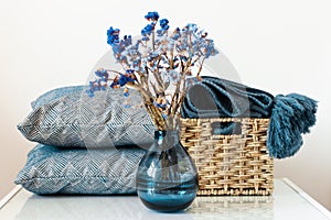 Cozy home interior decor: pillow, plaid, vase with flowers on a white shelf in the room. The quarantine concept of stay home