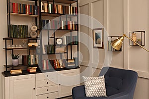 Cozy home library interior with collection of different books on shelves and comfortable place for reading