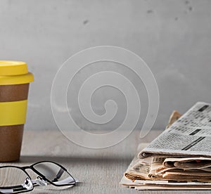 Cozy home scene - a stack of old read newspapers, glasses and a glass of coffee on a wooden table