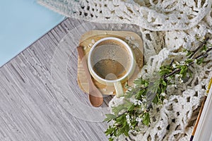 Cozy home still life: cup of hot coffee, spring flowers and opened book with warm plaid. Springtime concept, free copy