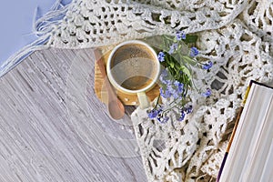 Cozy home still life: cup of hot coffee, spring flowers and opened book with warm plaid. Springtime concept, free copy