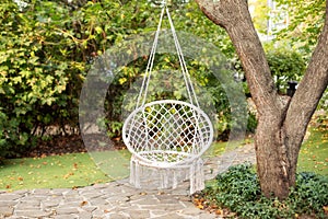 Cozy hygge place for weekend relax in garden.  Cozy exterior backyard. Concept of rest outdoor. Hammock chair in boho style hangin