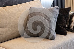 Cozy interior details. Decorative pillows in neutral colors, plaid on beige textile sofa. Home comfort concept, textiles,