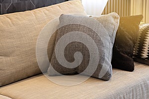 Cozy interior details. Decorative pillows in neutral colors, plaid on beige textile sofa, warm highlight. Home comfort concept,