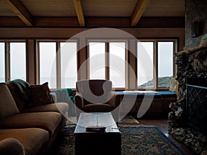 Cozy interior living room of a beach house on San Juan Island, with plush couches and chairs, window seats, and a stone