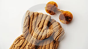 Cozy knitted woolen scarf and hat with pompoms in a warm caramel color, displayed on a white background