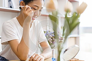 Cozy lifestyle concept, Young woman in turban after shower and apply eyeliner on eyelid for makeup