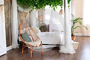 Cozy light bedroom in Scandinavian style bedroom, canopy bed and wicker rattan armchair.