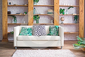 Cozy light room with plants, white sofa and stylish furniture in scandinavian style. Living room interior concept. Selective focus photo