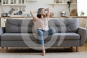 In cozy living room happy woman sitting on couch alone