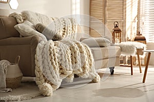 Cozy living room interior with beige sofa, knitted blanket and cushions