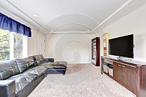 Cozy living room interior with black leather couch and tv set