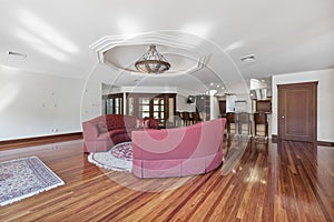 Cozy modern interior design of a living room with laminate flooring and a red couch in a mansion