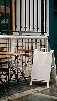 Cozy outdoor cafe with wooden table, metal railing, tiled section, and white signboard
