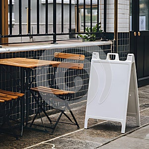 Cozy outdoor cafe with wooden table, metal railing, tiled section, and white signboard