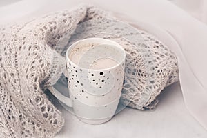 Cozy pastel knitwear and a cup of coffee on white marble windowsill. Close-up.