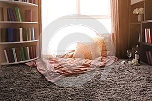 Cozy place for rest with pillows and soft plaid near window in room