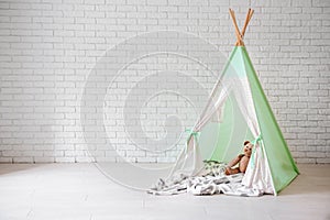 Cozy play tent for kids near white brick wall indoors