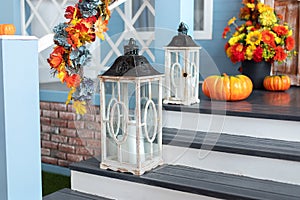 Cozy porch of the house with wooden lanterns in fall time. Halloween design home with yellow fall leaves and lamps.